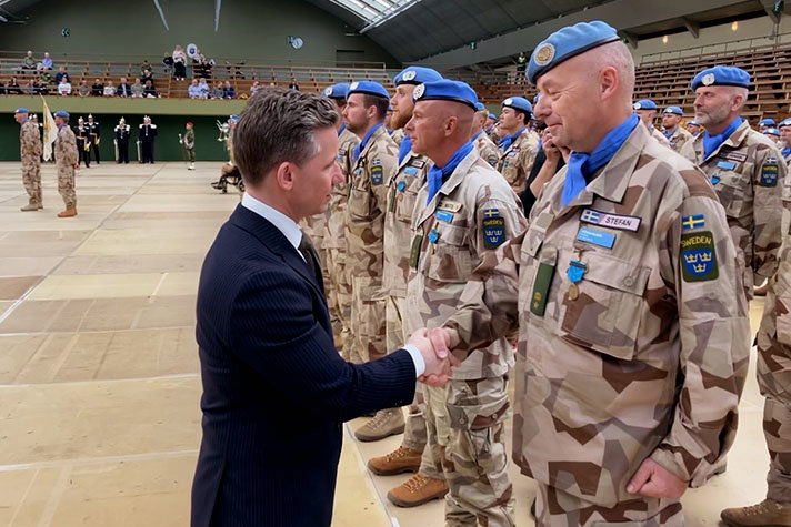 Försvarsminister Pål Jonson hälsar på svenska FN-soldater i militäruniform med ökenkamouflage. 