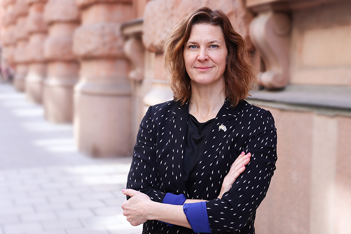 Porträttbild på Nina Larsson, fotad utomhus. Nina Larsson ser nöjd ut och håller armarna i kors.