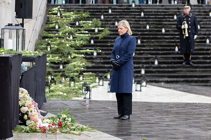 Andersson står framför en hög med blommor under en minnesceremoni på Sergels torg i Stockholm