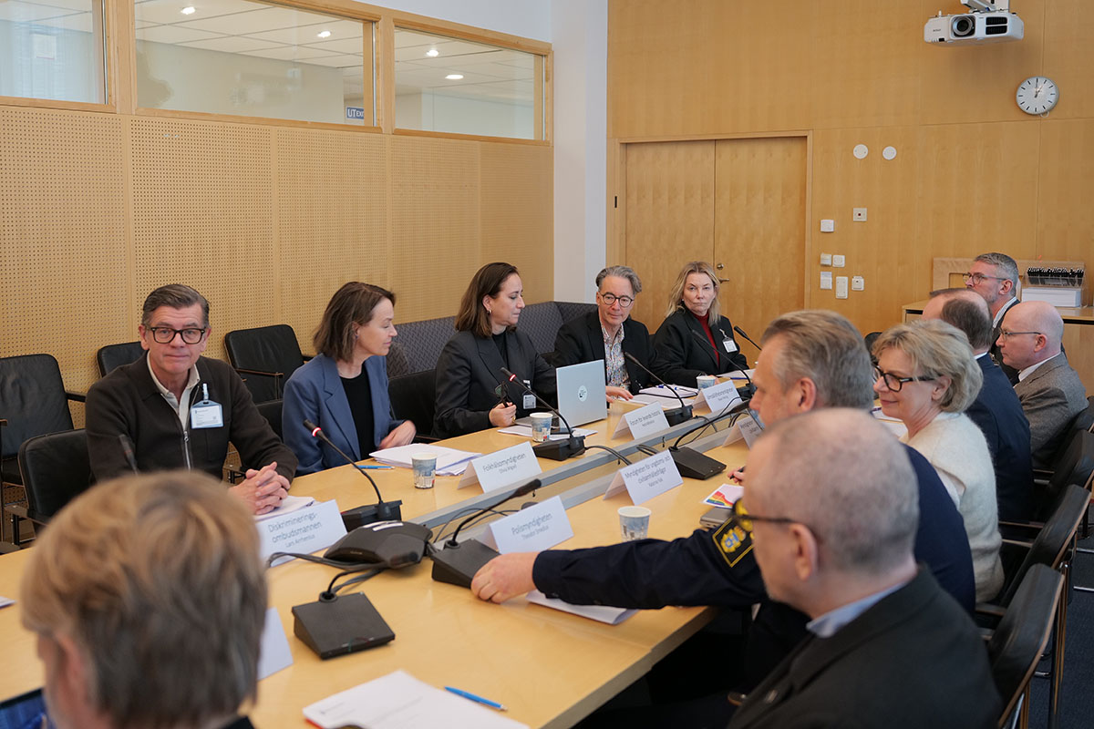 Flera personer sitter runt ett stort bord i ett sammanträdesrum.