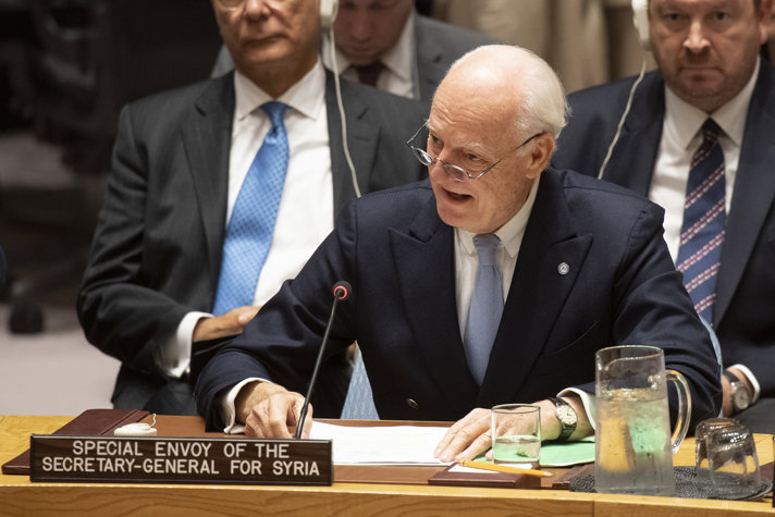 Staffan de Mistura lutar sig fram för att tala i mikrofonen.