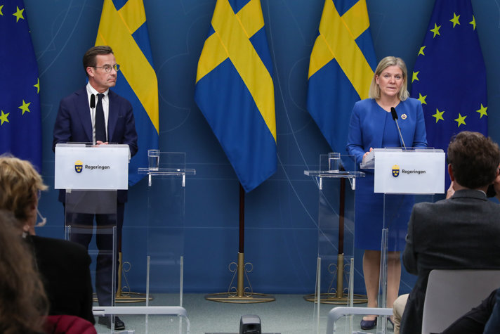 Statsminister Magdalena Andersson och Moderaternas partiledare Ulf Kristersson står vid var sin talarstol med svenska flaggor i bakgrunden.