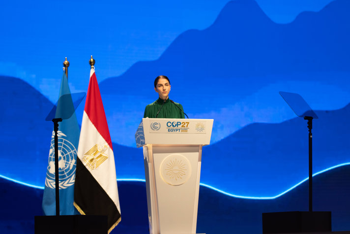 Klimat- och miljöminister Romina Pourmokhtari håller tal vid ett podium på en stor scen i plenisalen på COP27