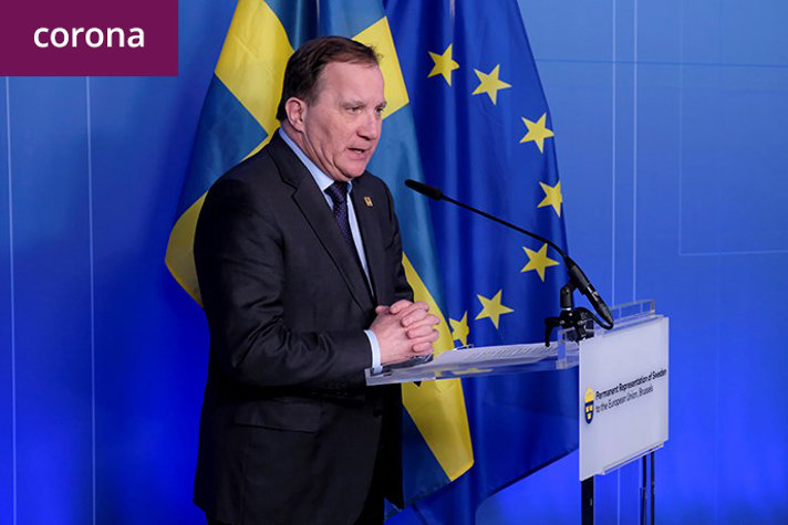Stefan Löfven står vid ett podium. Bakom finns svenska flaggan och EU-flaggan. 