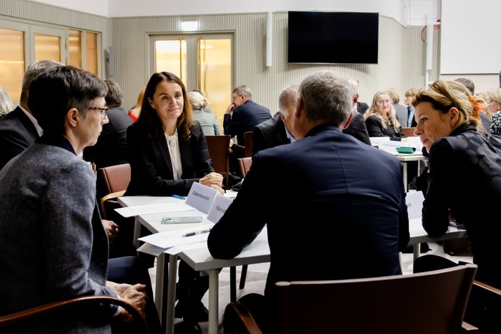 Flera personer sitter runt bord och diskuterar.