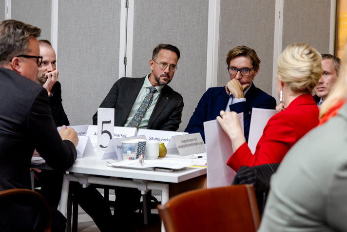 Flera personer sitter runt ett bord och pratar.