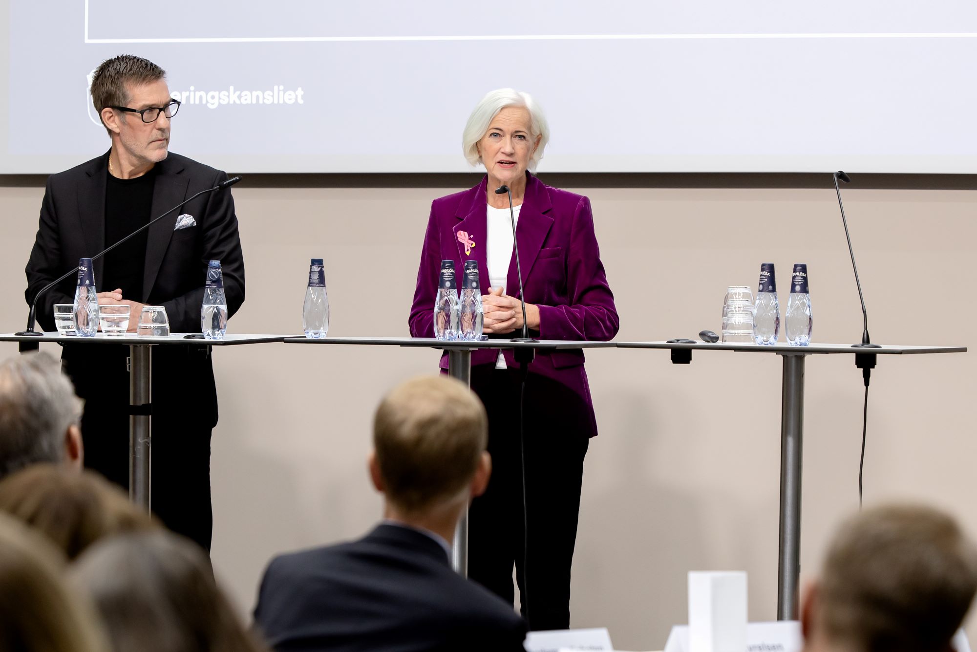 Två personer står på en scen och pratar.