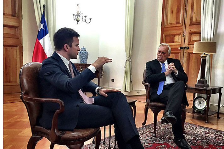 Gabriel Wikström och Jorge Burgos sitter och samtalar i ett rum. I bakgrunden syns Chiles flagga.