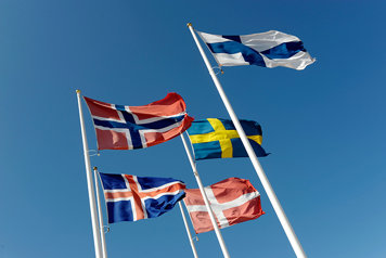 Nordens flaggor fladdrar i vinden på flaggstänger sett strax nedanfrån
