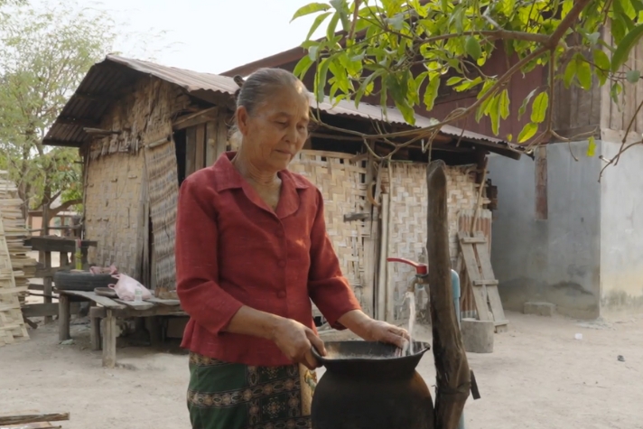 Kvinna som fyller en behållare med vatten från en kran.