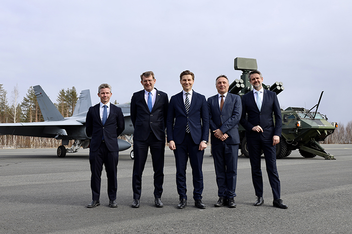 De nordiska försvarsministrarna står på rad utomhus och i bakgrunden syns flygplan. 