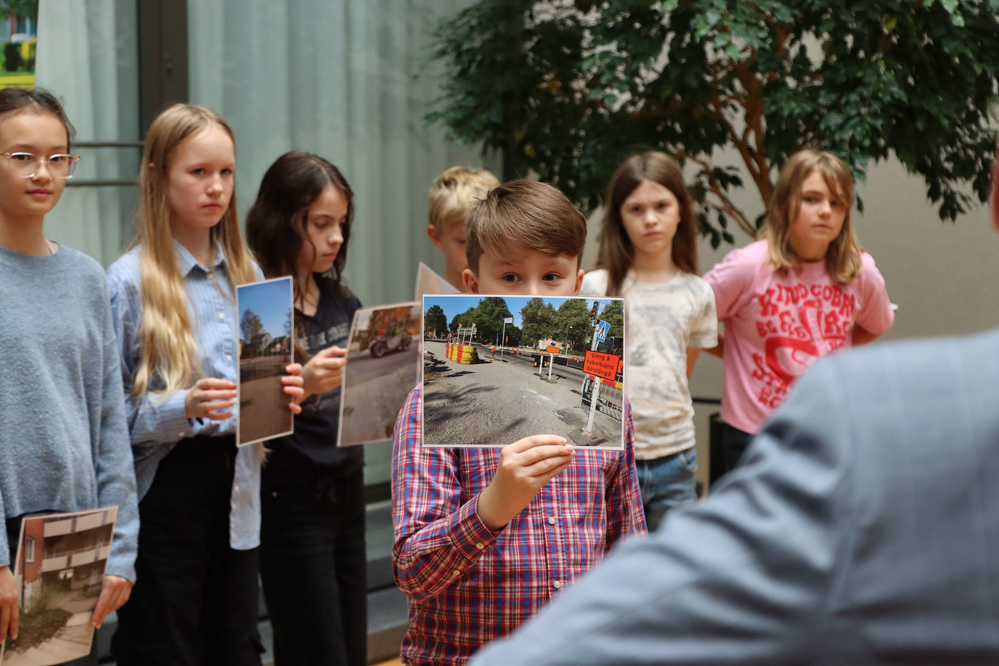 En pojke håller upp ett foto av en gata.
