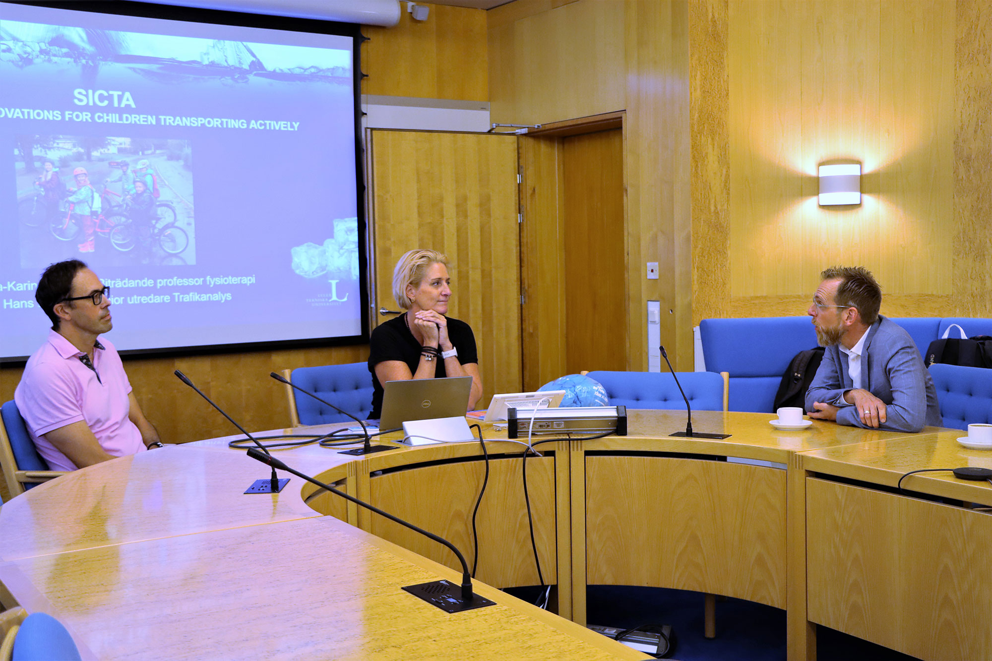 Tre personer sitter vid ett stort konferensbord.