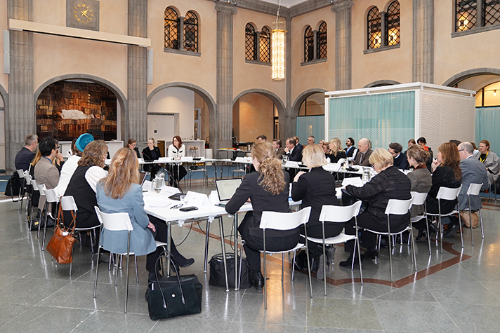 Delatagarna i mötet sitter vid bord i en fyrkant. Bilden är på alla.