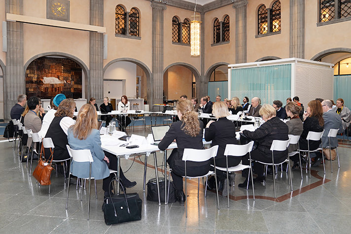 Delatagarna i mötet sitter vid bord i en fyrkant. Bilden är på alla.