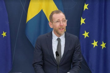 Socialminister Jakob Forssmed står vid en talarpulpet.