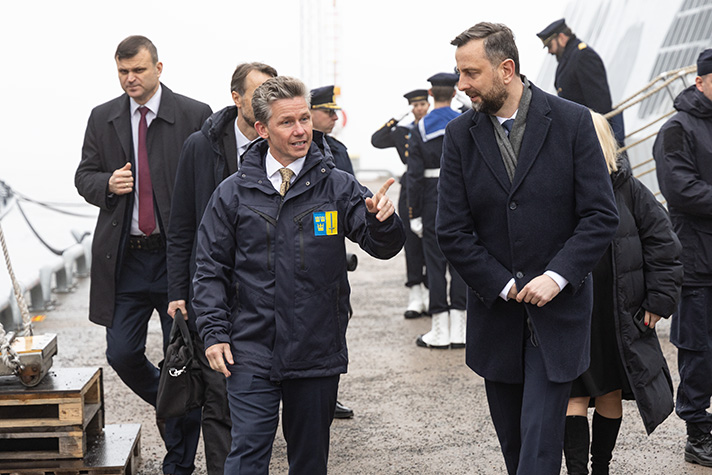 Pål Jonson och Władysław Kosiniak-Kamysz går längs en kaj lämnandes korvette Härnösand. De samtalar och ler. Bakom står annan personal och sjömän. 