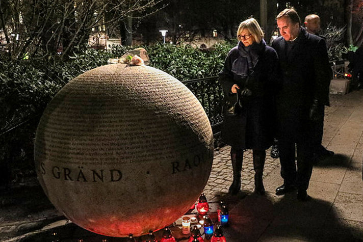 Statsminister Stefan Löfven och hans hustru Ulla Löfven står med böjda huvuden vid minnesmonumentet för förintelsens offer.amför