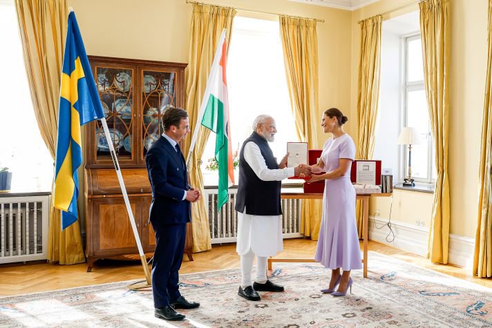 Premiärminister Narendra Modi skakar hand med kronprinsessan när han tar emot orden. Ulf Kristersson står till vänster.