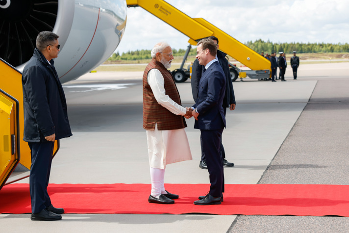 Ulf Kristersson skakar hand med Narendra Modi. Bakom dem syns en flygplansmotor.
