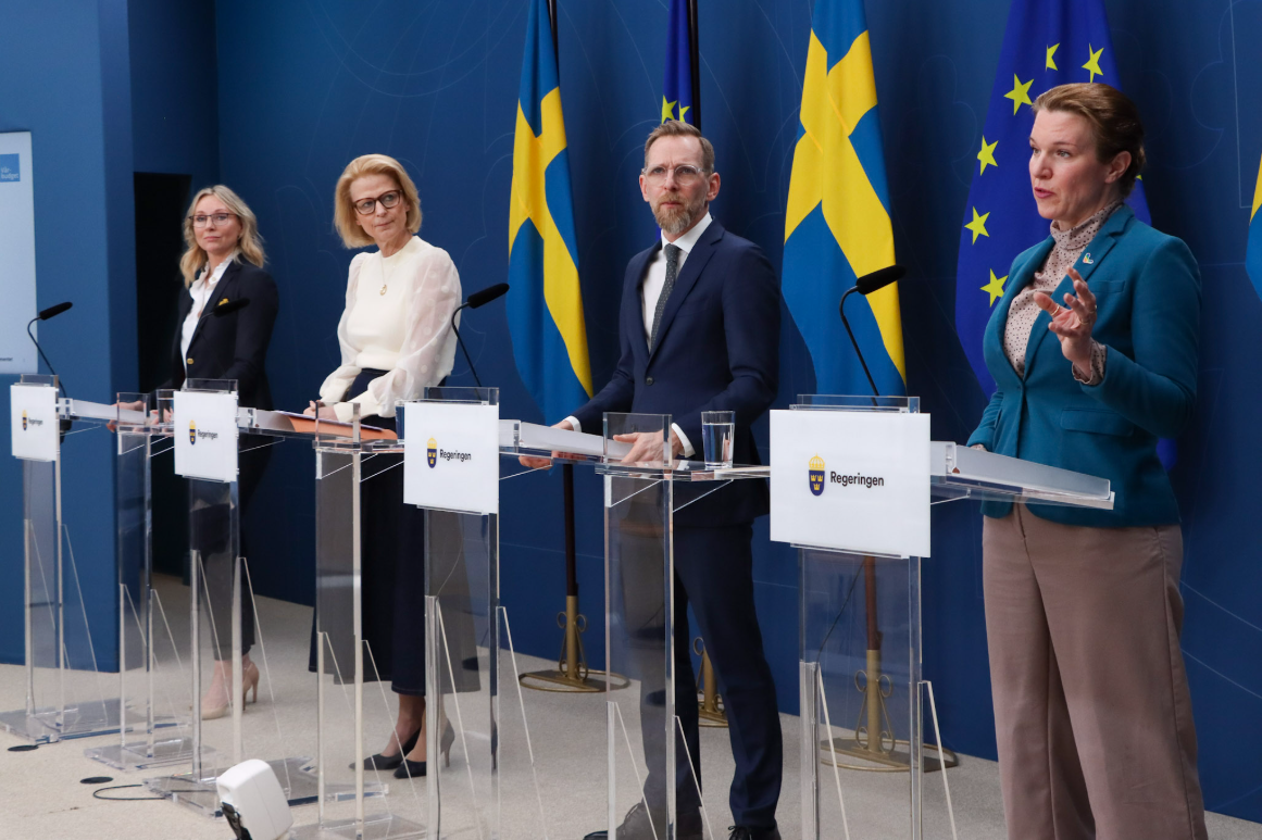 Fyra personer håller pressträff. De står bakom var sin talarstol.