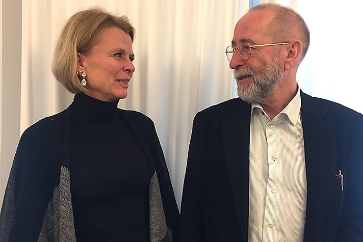 En blond kvinna och en man i mörk kavaj talar med varandra.