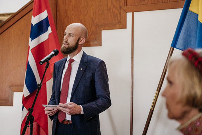 Minister för civilt försvar Carl-Oskar Bohlin håller tal. I bakgrunden syns den norska och svenska flaggan. 