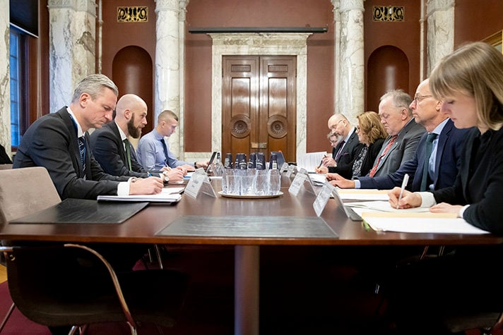 Mötets andra dag inleds av Carl-Oskar Bohlin. Foton visar mötesdeltagarna sittandes runt ett avlångt bord. 