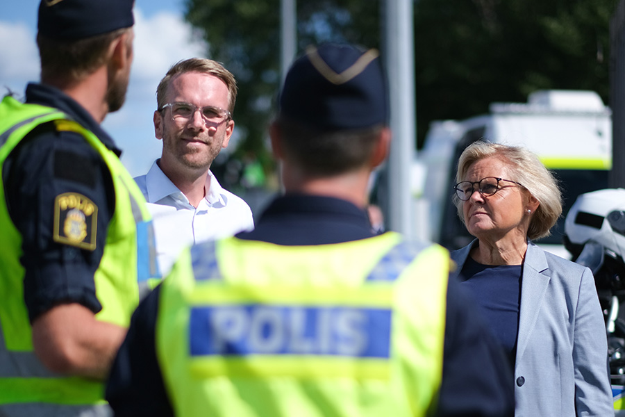 Infrastruktur- och bostadsminister Andreas Carlson och rikspolischef Petra Lundh pratar med poliser vid en trafikkontrollplats.