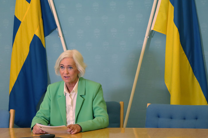 Sjukvårdsminister Acko Ankarberg Johansson talar. Hon håller talkort i handen och bakom henne finns en svensk och en ukrainsk flagga.