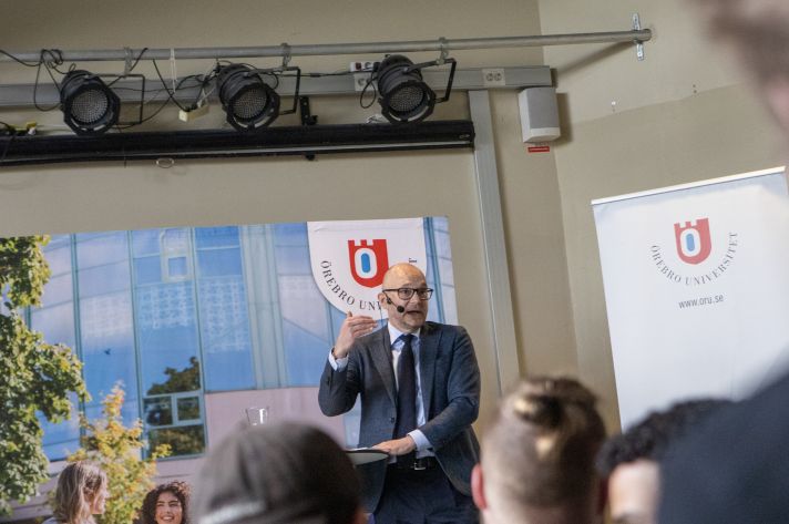 Johan Britz står på en scen och föreläser för studenter på Örebro universitet.