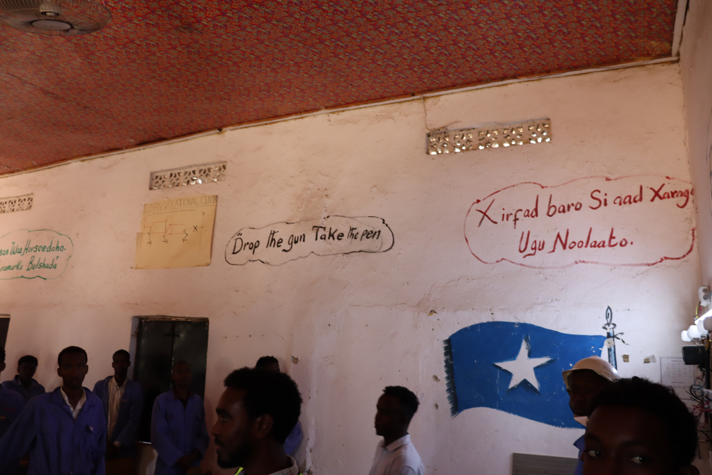 En vit stenvägg med orden "Drop the gun take the pen"