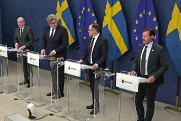 Fyra personer står sedda snett uppifrån står vid var sin talarstol