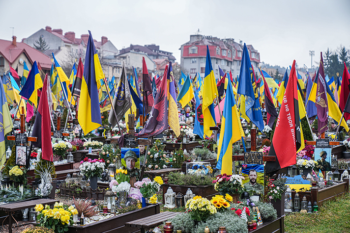 Kyrkogård fylld av bilder på stupade soldater, blommor och ukrainska flaggor.