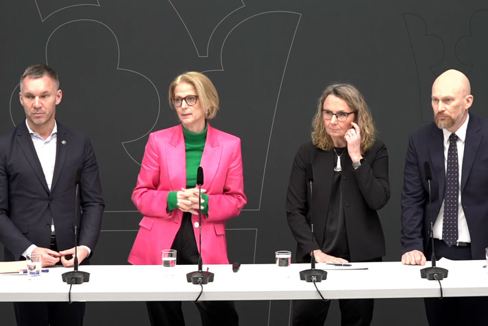 De medverkande står bakom ett långbord med mikrofoner på