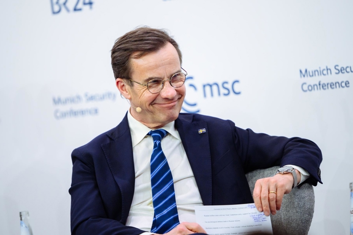 Statsminister Ulf Kristersson sitter i ett panelsamtal, men en bakgrund med Munich Security Conferances logotyp.