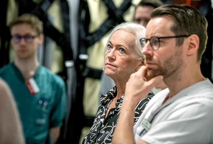 Acko Ankarberg Johansson i sjukhusmiljö omgiven av sjukvårdspersonal.