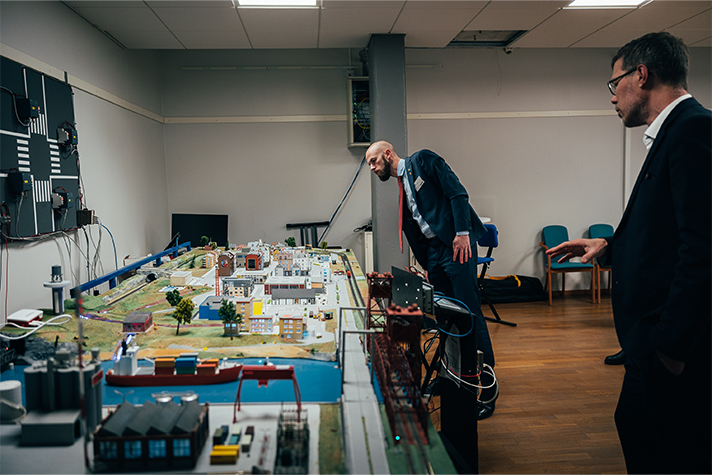 Minister för civilt försvar Carl-Oskar Bohlin enhetschef Jonas Hallberg från FOI tittar på en modell av ett samhälle som står på ett bord.
