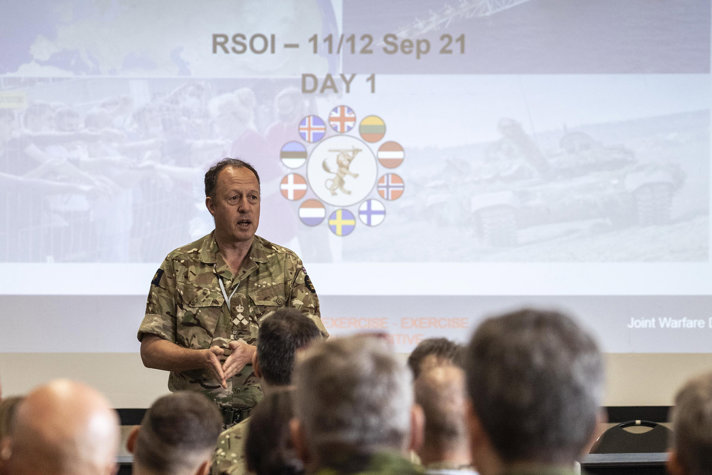 En man i militärkläder föreläser för en grupp deltagare i övningen.