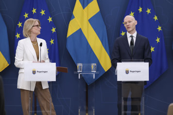 Finansministern och finansmarknadsministern står vid talarstolar och pratar.