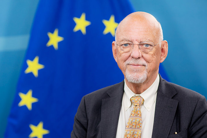 Bild på EU-minister Hans Dahlgren. I bakgrunden syns en EU-flagga.