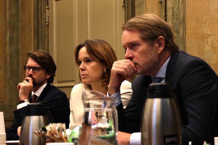 Tre personer sitter bredvid varandra i ett mötesrum.