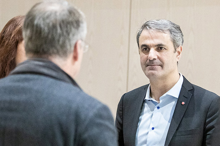 Näringsminister Ibrahim Baylan står och samtalar med två personer som har ryggen mot kameran