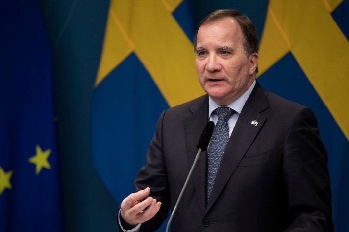Statsminister Stefan Löfven talar under en presskonferens, med EU-flaggan och Sveriges flagga i bakgrunden.