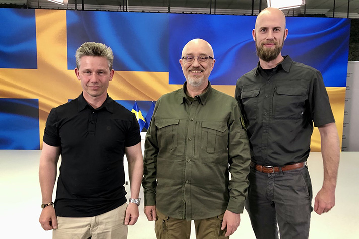 försvarsminister Pål Jonson står tillsammans med Ukrainas försvarsminister Oleksij Reznikov och minister för civilt försvar Carl-Oskar Bohlin med den svenska och ukrainska flaggorna på stor skärm i bakgrunden.  
