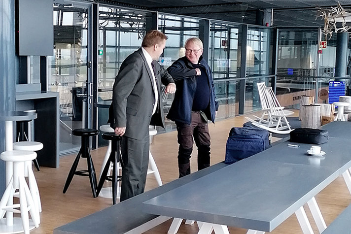 Antti Kaikkonen och Peter Hultqvist gör en "coronahälsning" med armbågarna i sammanträdesrum på den finska flygbasen i Rovaniemi.