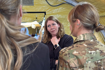 Elisabet Lann i ett stort militärtält och pratar med två kvinnor. En av kvinnorna har militäruniform på sig.