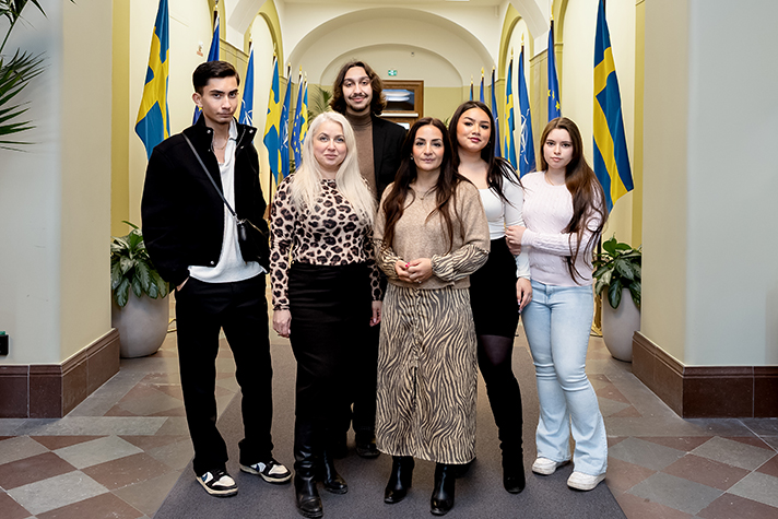 Gruppbild med kulturministern i mitten och rådet runt henne. I bakgrunden syns en korridor med flaggor.