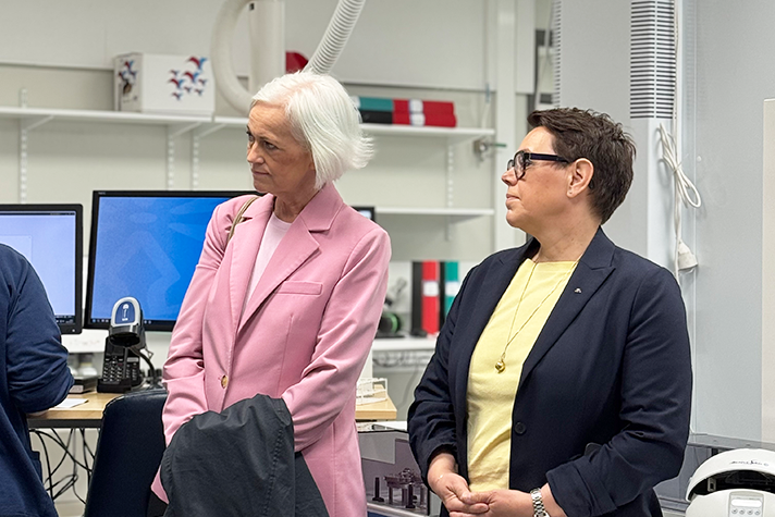 Två kvinnor i en sjukhusmiljö lyssnar och tittar intensivt.