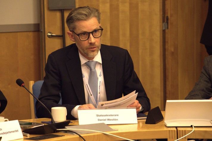 Statssekreteraren håller anförande och har ett papper med talepunkter.